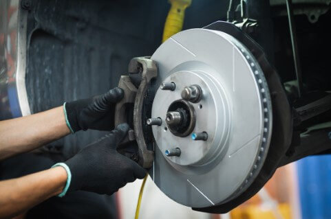 Image of mechanics on the brake calipers about to perform a brake service. 