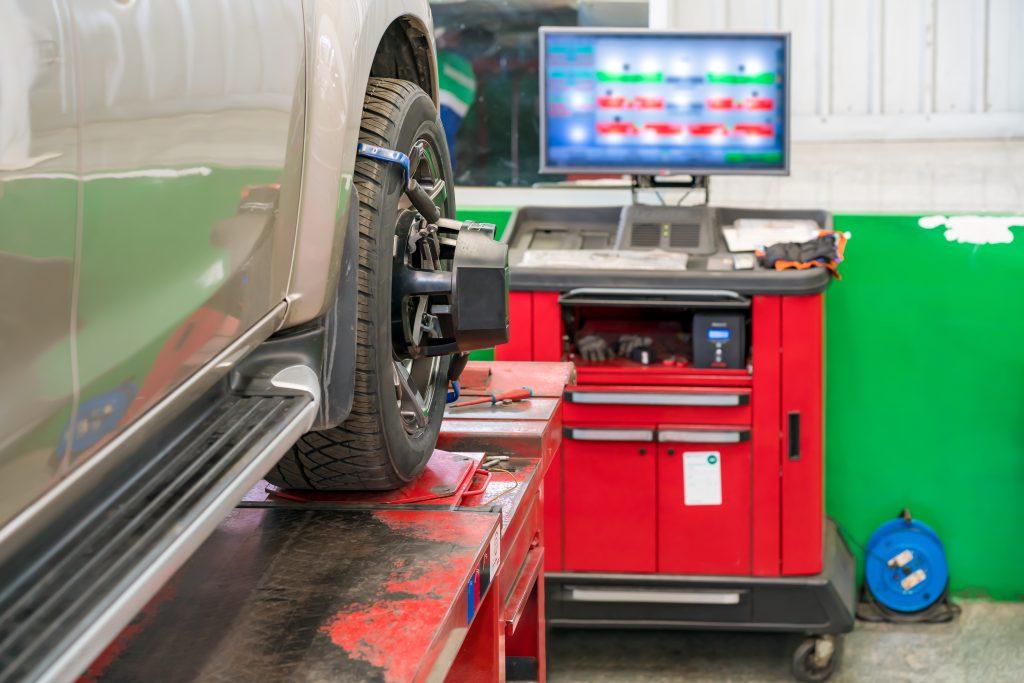 Image of a vehicle on an alignment rack with a computer facing in front of it. The vehicle is getting serviced