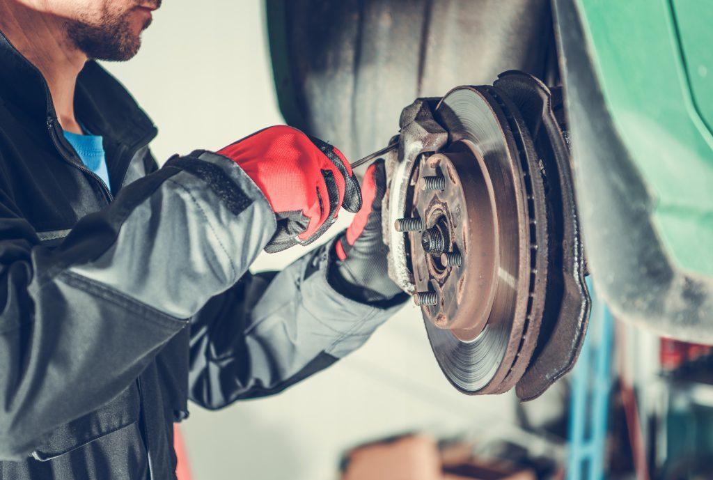 Image of a mechanic working on the brakes on a vehicle. 