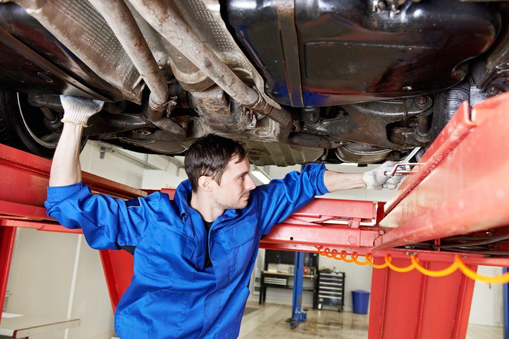 image of a mechanic under a vehicle performing an alignment service.