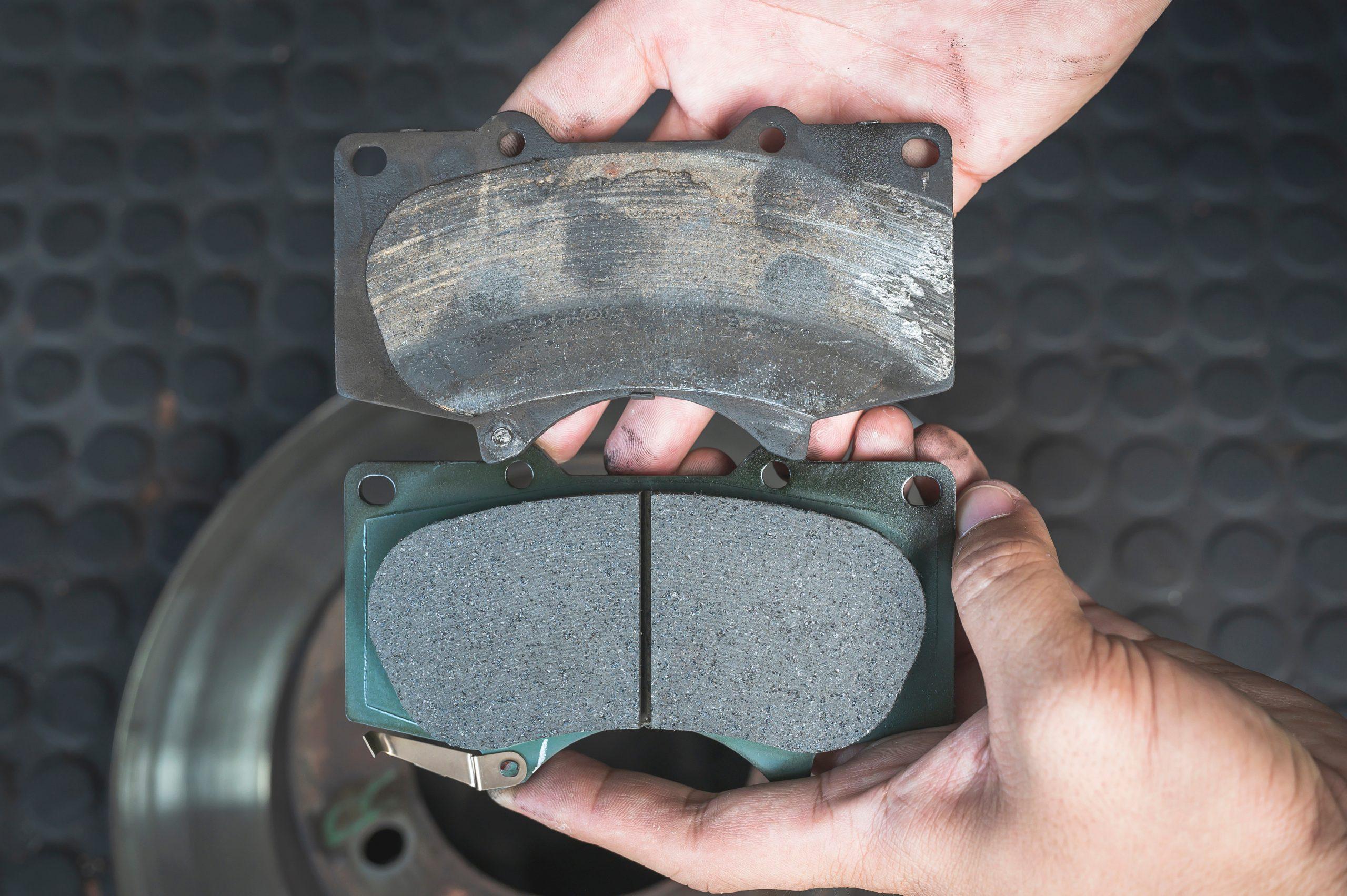 Image of worn down brake pads in one hand and a brand new one in the other hand.