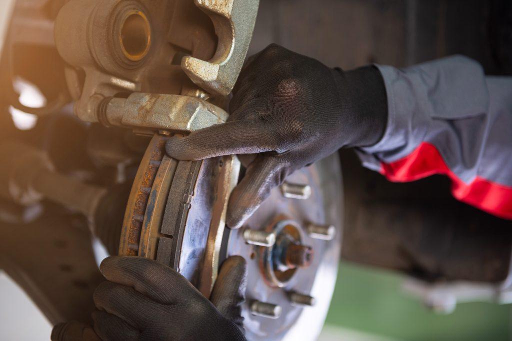 Image of mechanic taking brake pads out of a caliper. 