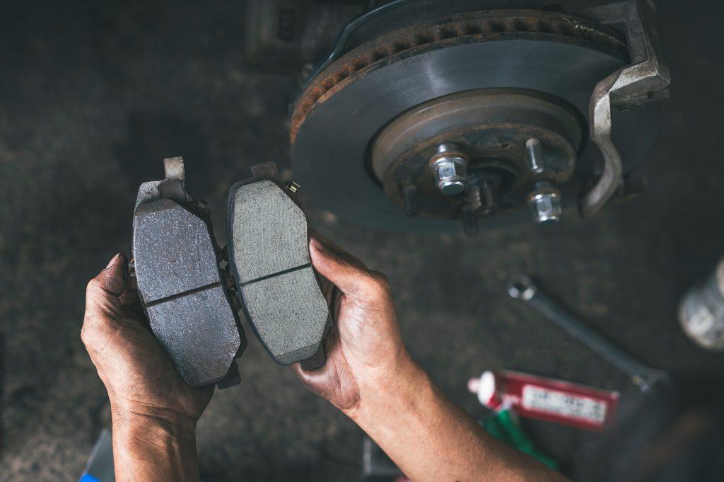 Mechanic hands holding pads about to perform a brake service.