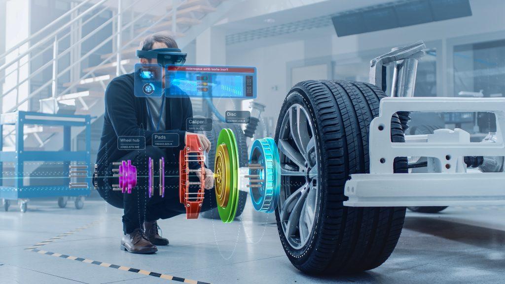 A man on one knee with digital displays showing what a wheel has, hub, pads, calipers, rotors.