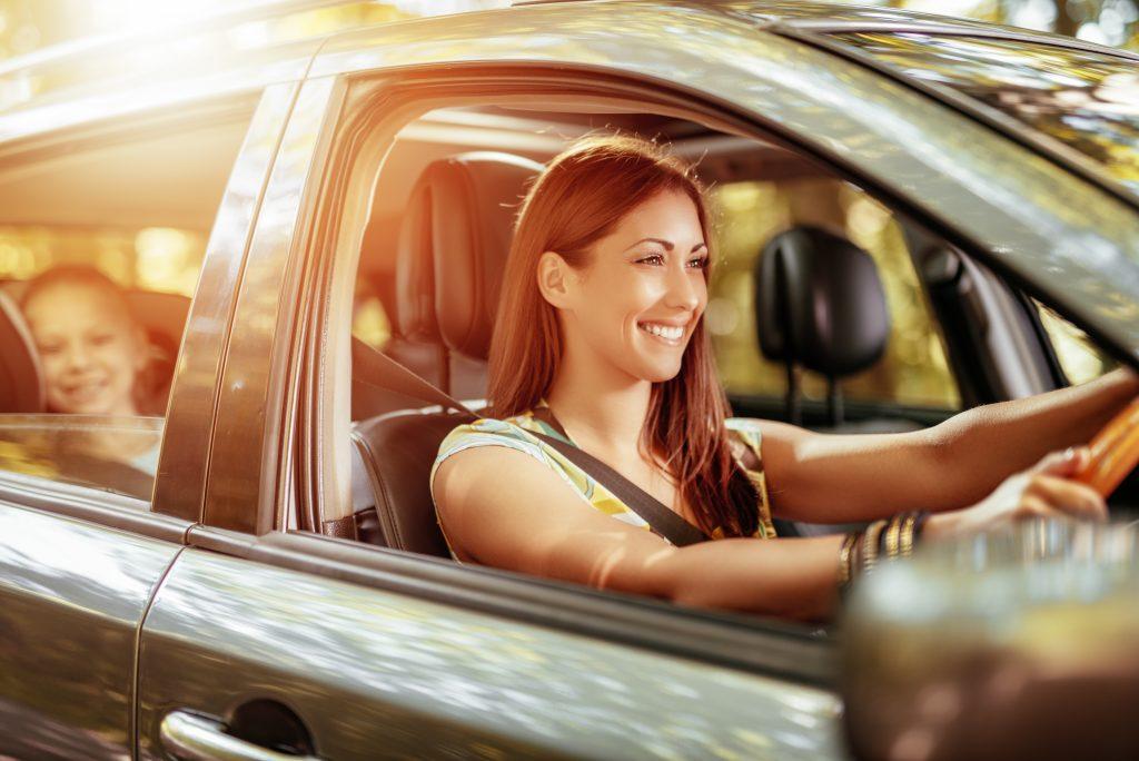 image of a woman smiling and driving her daughter.