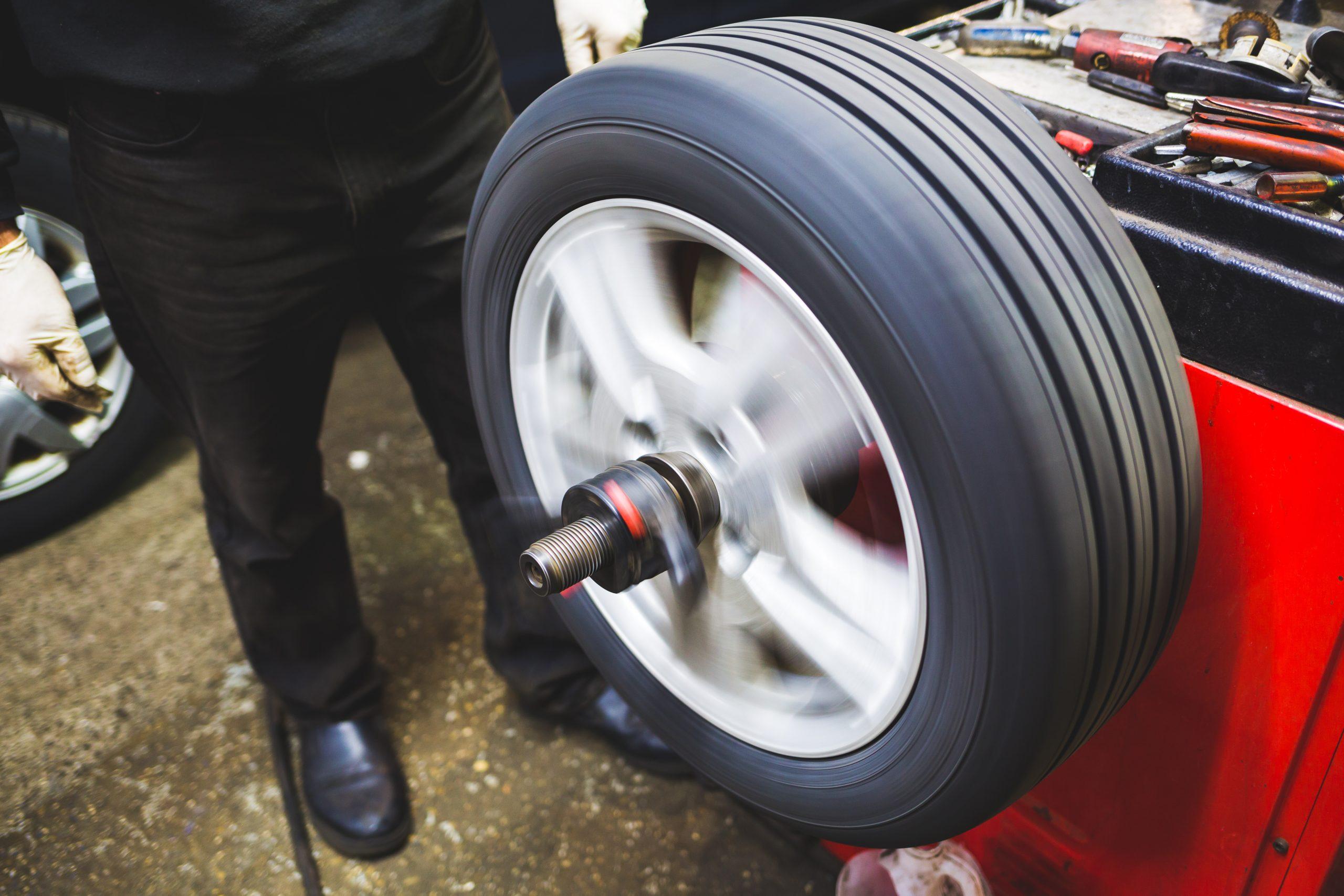 Mechanic balancing a tire on tire balancing machine.