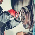 Mechanic performing a brake service on a vehicle. Changing out rotors and pads.