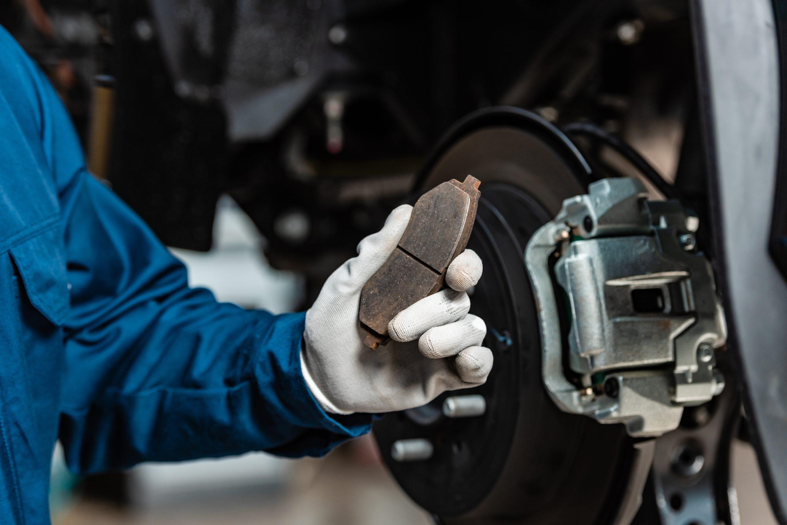 Mechanic holding pads next to the vehicle performing a brake service.