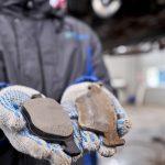 Mechanic hands with brakes pads, one is old fully worn and the other one is new