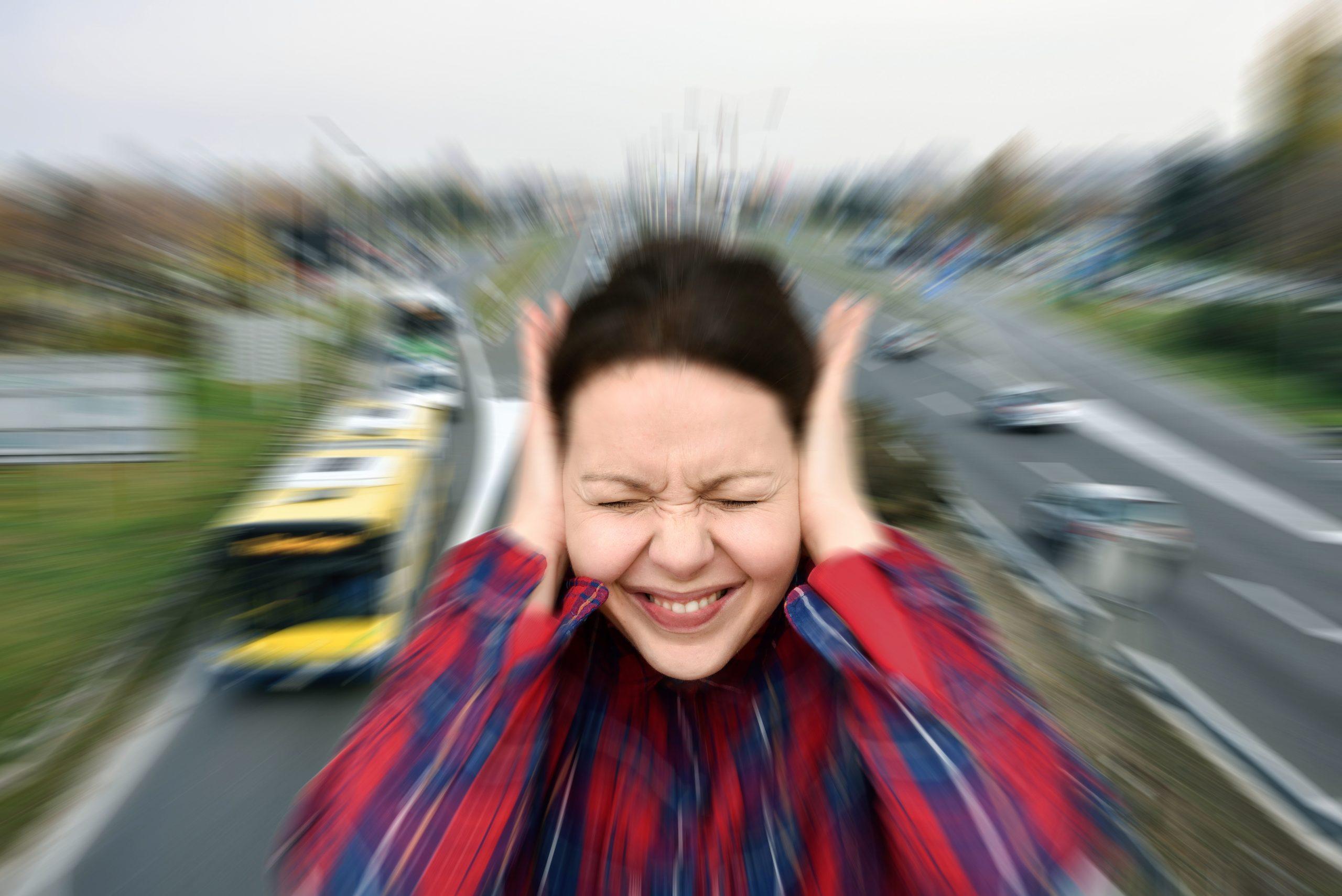 Image of a women covering her ears because of the street traffic