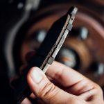 Image of mechanic hand holding a worn down brake pad.