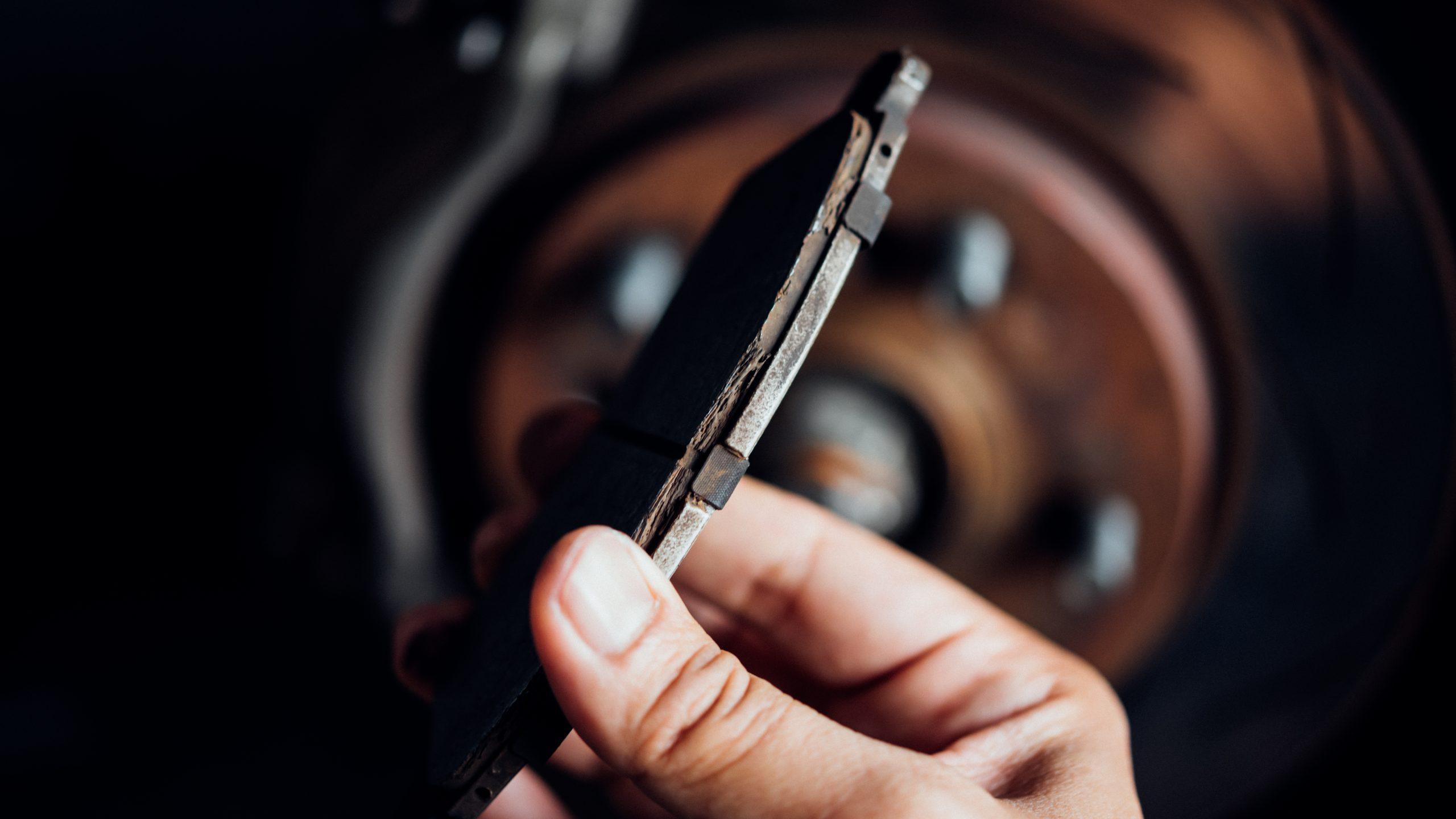 Image of mechanic hand holding a worn down brake pad.