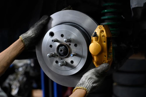 Image of a mechanic hands holding the rotor to perform an inspection on the brakes