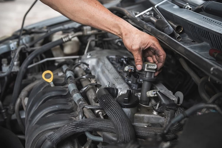 image of mechanic pulling out a ignition coil to perform a spark plug service