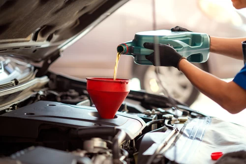 image of a mechanic pouring oil into a funnel for an oil change.