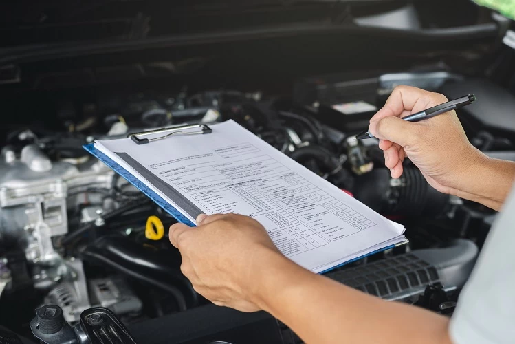 image of a mechanic holding a clip board doing his inspection