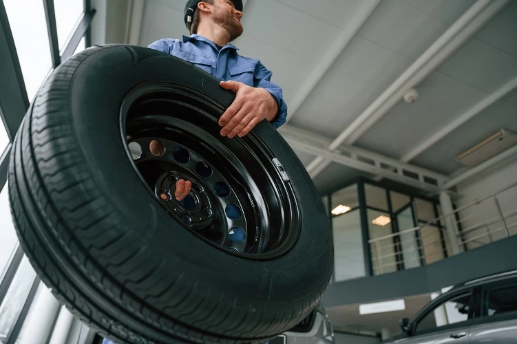 image of tire tech holding a tire about to change it out.